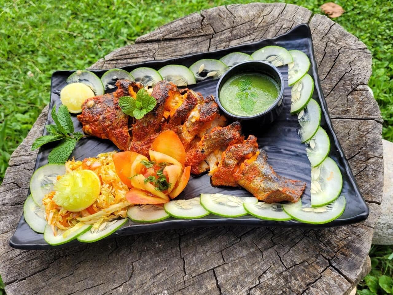A kitchen platter of tandoori and salad on a wooden stump