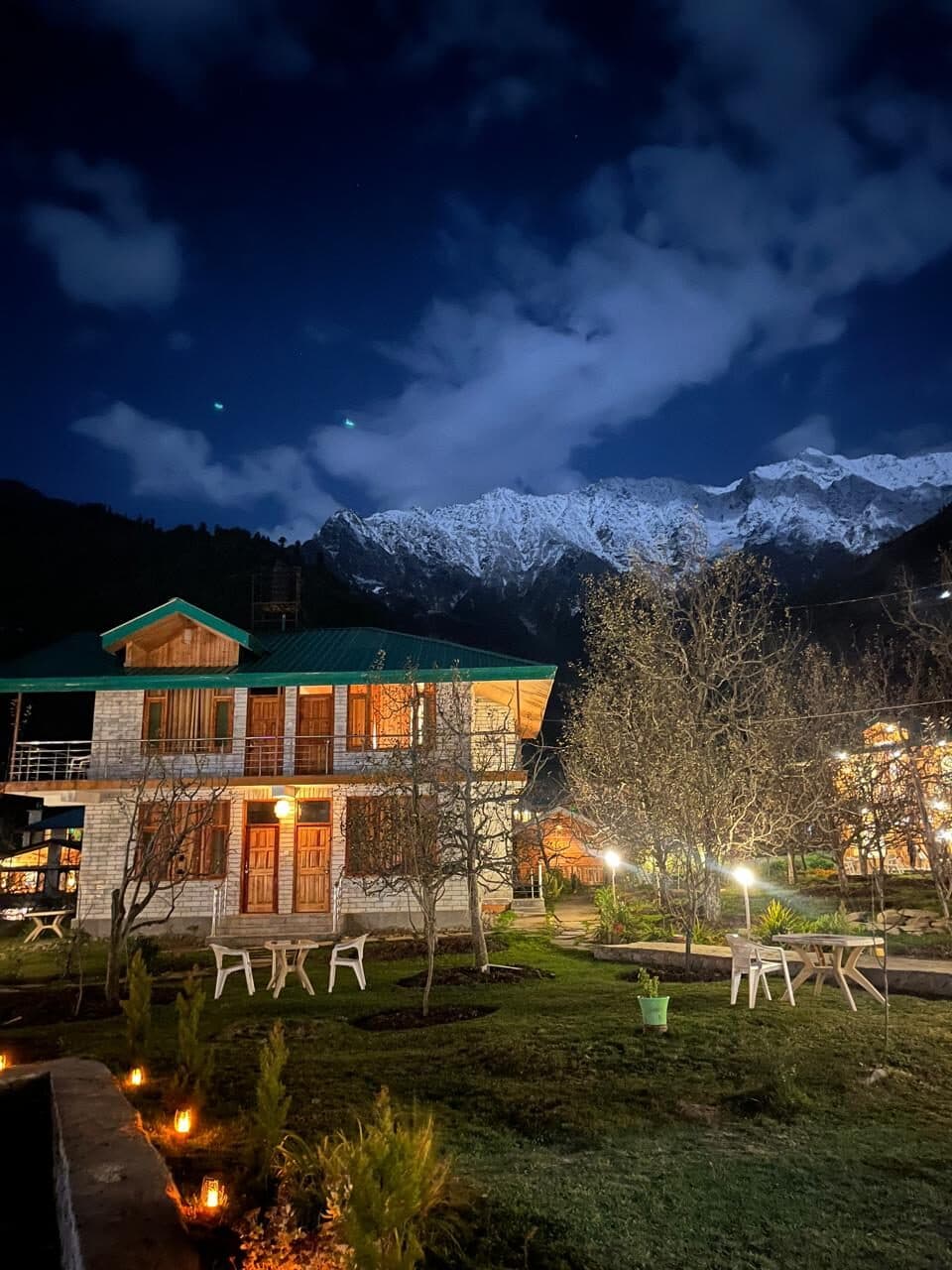 The Shanag chalets glowing at night beneath snow peaks and cloud